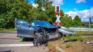 Ein beschädigtes Auto steht an einem Bahnübergang.