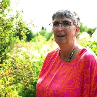 Ulrike Amler steht in ihrem Garten in Rutesheim. Im Hintergrund sind Sträucher zu sehen.