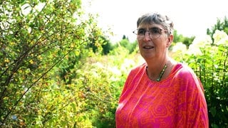 Ulrike Amler steht in ihrem Garten in Rutesheim. Im Hintergrund sind Sträucher zu sehen.