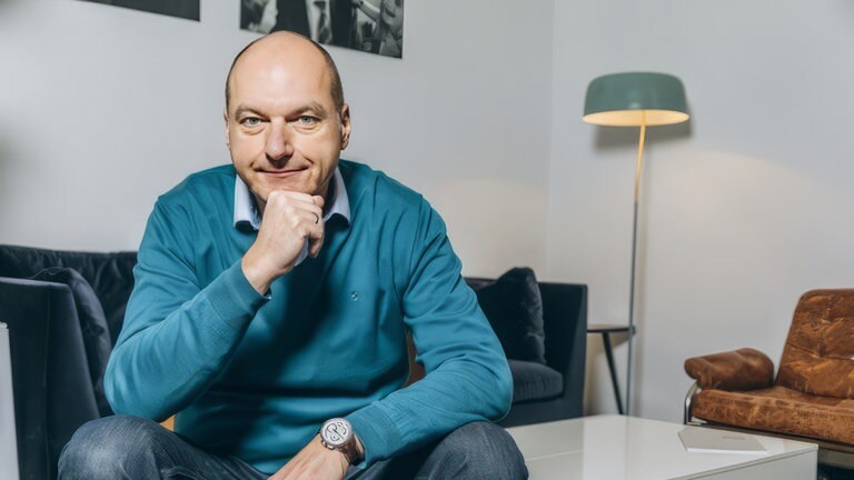 Politikberater Frank Stauss hält die Faust ans Kinn und schaut in die Kamera. 