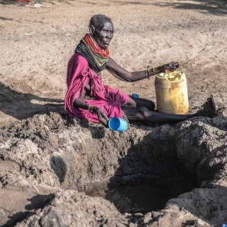 Eine Turkana versucht, in Kakuma (nordwestliches Turkana County in Kenia) versickertes Grundwasser aus einem ausgetrockneten Flussbett zu schöpfen: Weltweit ziehen rund 100 Millionen Nomaden durch meist karge Regionen in Afrika und Asien. Der Klimawandel erschwert die Suche nach Wasser und Weideland. 