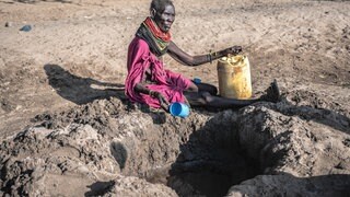 Eine Turkana versucht, in Kakuma (nordwestliches Turkana County in Kenia) versickertes Grundwasser aus einem ausgetrockneten Flussbett zu schöpfen: Weltweit ziehen rund 100 Millionen Nomaden durch meist karge Regionen in Afrika und Asien. Der Klimawandel erschwert die Suche nach Wasser und Weideland. 