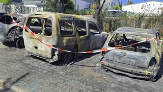 Auf einen Parkplatz im rheinhessischen Harxheim stehen drei völlig ausgebrannt Autos. Der tatort wurde von der Polizei mit rot-weißem Flatterband abgesperrt.