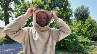 Ein Kammerjäger in einem insektenstichresistenten Anzug.