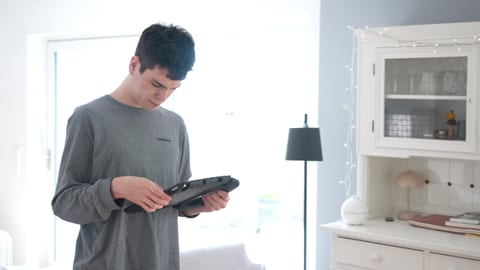 Elias steht im Raum und schaut auf sein Handy. Er ist eins von vielen Kindern mit Autismus, die Unterstützung brauchen.