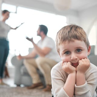 Ein Kind guckt traurig während die Eltern sich streiten | Psychologin Katharina Grünewald über die Auswirkungen von Trennung und Scheidung auf Kinder