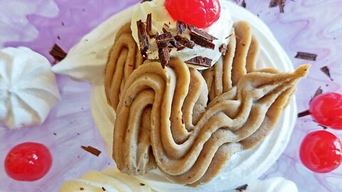 Süße Maronencreme mit Baiser: Das Dessert von oben aus der Totale fotografiert. Es ist mit roten Cocktailkirschen garniert. Auf dem Teller daneben liegen mehrere Stücke von Baiser.