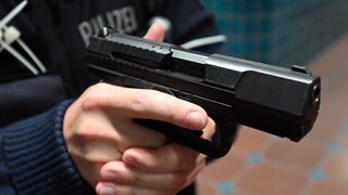 Ein Polizist hält eine Pistole vom Typ Walther P99 in den Händen.