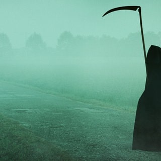 Der Tod, in Gestalt eines Sensemann, steht allein in einer weiten, nebeligen Landschaft