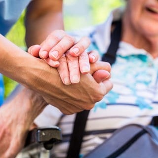 Ältere Frau und Pflegerin Hand in Hand