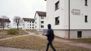Ein Geflüchtetet läuft an Gebäuden im Aufnahmezentrum in Heidelberg vorbei.