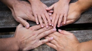 Symbolfoto: Eine Familie hält sich an den Händen. Wieso wird man zu Pflegeeltern? Ein Pflegevater erzählt. 