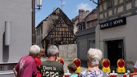 Hinter der Absperrung versammeln sich immer wieder Bürgerinnen und Bürger. Sie machen Fotos von den zerstörten Gebäuden. 