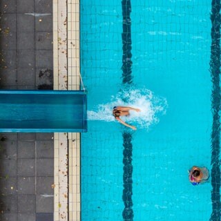 Menschen schwimmen in einem Freibadbecken, das von oben gefilmt ist