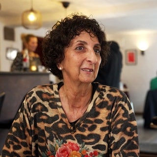 Tatjana Pannone sitzt in einem Café. Sie hat kurze, braune Locken und trägt ein Leoparden-Shirt.