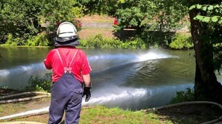 Feuerwehrmann blickt auf die Jagst - Mühlenbrand löste Fischsterben aus