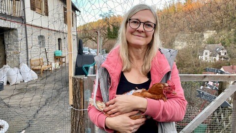 Henne Frieda auf dem Arm von Manuela Lang im Garten. Seit September lebt das gerettete Huhn bei Manuela Lang in Haigerloch - und fühlt sich schon sichtlich wohl.