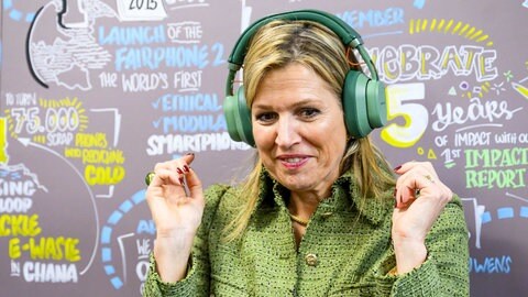 Königin Máxima der Niederland hat grüne Kopfhörer auf und scheint dazu zu tanzen.