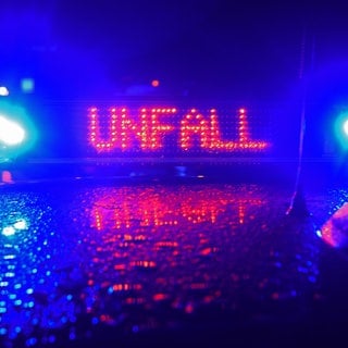 Polizeiauto mit blauen Sirenen. Auf dem Dach die leuchtende Anzeige: Unfall