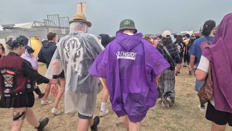 Menschen in Regenschutz verlassen das Festival-Gelände. Das Southside gehört zu den größten Rockfestivals Deutschlands.