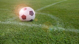 Ein Fußball auf grünem Rasen.