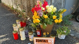 Nach den Schüssen in Offenburg haben Menschen Blumen und Kerzen für das 36-jährige Opfer abgelegt. Auf einem Schild steht "Nein zu Gewalt gegen Frauen". 