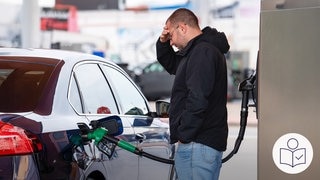Ein Mann steht an einer Tankstelle. Er tankt sein Auto auf. Der Mann hält die Hand an die Stirn. Rechts das SWR Logo für Leichte Sprache.