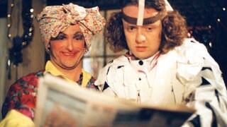 Toni und Bernhard sind verkleidet und lesen in einer Zeitung