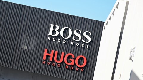 Das Logo des Modekonzerns Hugo Boss auf einer schwarzen Fassade in rot und weiß.