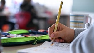 In einer Grundschule arbeitet ein Schüler einer vierten Klasse an in einem Heft an seinen Mathematikaufgaben.
