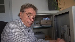 Älterer Mann öffnet einen Tresor.
