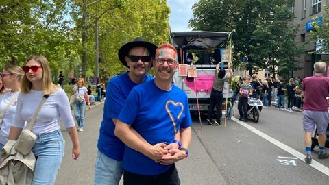 Andy (links) und Thommy (rechts) umarmen sich beim CSD Stuttgart 2025.