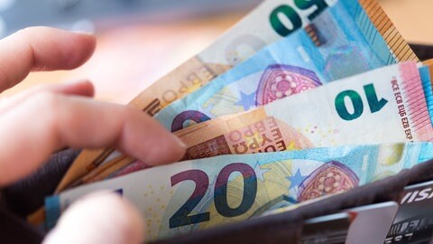 Eine Person hält eine Geldbörse mit Banknoten in der Hand. Schon im Koalitionsvertrag haben Grüne und CDU festgehalten, dass sie die Zahl der Landesbeschäftigten in der zentralen Verwaltung um mindestens fünf Prozent reduzieren wollen.