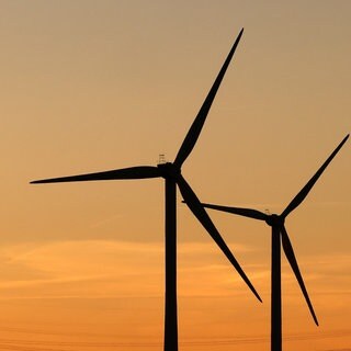 Strommasten und Windräder im Sonnenuntergang
