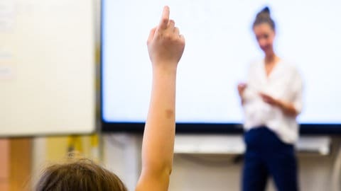 Ein Schüler meldet sich per Handzeichen in einem Klassenraum. (Symbolbild)