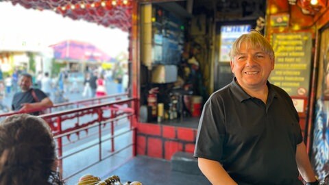 Rudolf Schütze steht vor seiner Gruselbahn auf dem Frühlingsfest. Seit 60 Jahren, also seit seiner Geburt, ist er praktisch mit dabei beim Familienunternehemen.