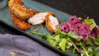 Wiener Backhendl: Wie im Rezept beschrieben, schmeckt es knusprig und saftig zugleich. Es ist auf einem Teller mit Salat präsentiert.