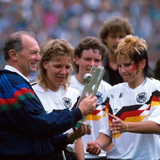Fußball-Bundestrainer Gero Bisanz übergibt den EM-Pokal an Spielerin Ursula Lohn (2.v.r.)
