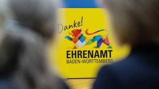 Eine überdimensionale Ehrenamtskarte steht während einer Pressekonferenz im Sozialministerium Baden-Württemberg auf dem Boden.