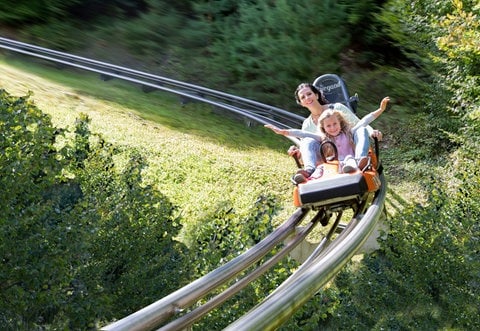 Eine Frau und ein junges Mädchen vergnügen sich auf der Sommerroddelbahn im Eifelpark.