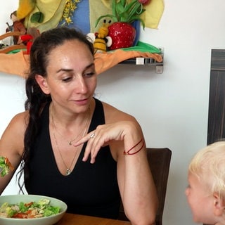 Tanzlehrerin Lea Grünwald sitzt mit einem kleinen Kind am Tisch und isst.