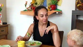 Tanzlehrerin Lea Grünwald sitzt mit einem kleinen Kind am Tisch und isst.