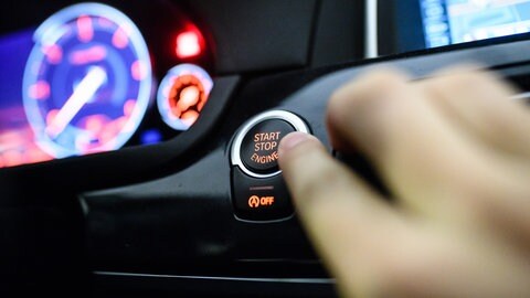 Ein Mann drückt den Start-Stop-Knopf eines Autos (Symbolbild).