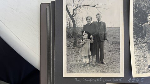 Schwarz-Weiss-Foto einer Familie, Mutter mit zwei Kindern vor einem Baum. (Zeitzeuge Heinz Weinkauf blickt zurück auf die Bombardierung und zerstörte Stadt Zweibrücken vor gut 80 Jahren.)