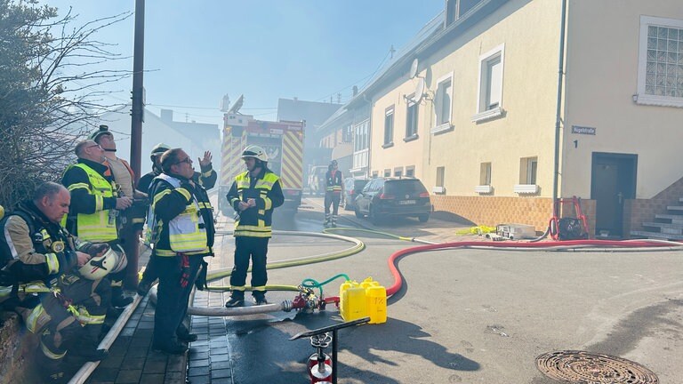 Feuerwehrleute machen Pause in der Bekämpfung des Brandes in Nanzdietschweiler im Kreis Kusel