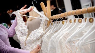 Brautkleider hängen bei einer Hochzeitsmesse auf einem Kleiderständer. 