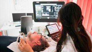 Dr. Eckart von Hirschhausen wird von Neurologin Dr. Taraneh Ebrahimi mit Ultraschall auf Plaque untersucht – eine mögliche Ursache für vaskuläre Demenz, die zweithäufigste Erscheinungsform der Demenz. – ARDWDR HIRSCHHAUSEN UND DAS GROßE VERGESSEN