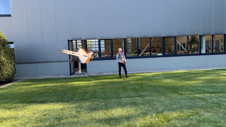 Ein Mann fliegt eine Drohne über eine Rasenfläche.