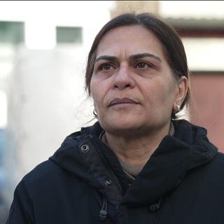 Eine Frau steht neben dem explodierten Haus