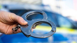 Symbolbild von Handschellen: Eine junge Frau sitzt in U-Haft, weil sie die Getränke von Kollegen mit Medikamenten versetzt haben soll.